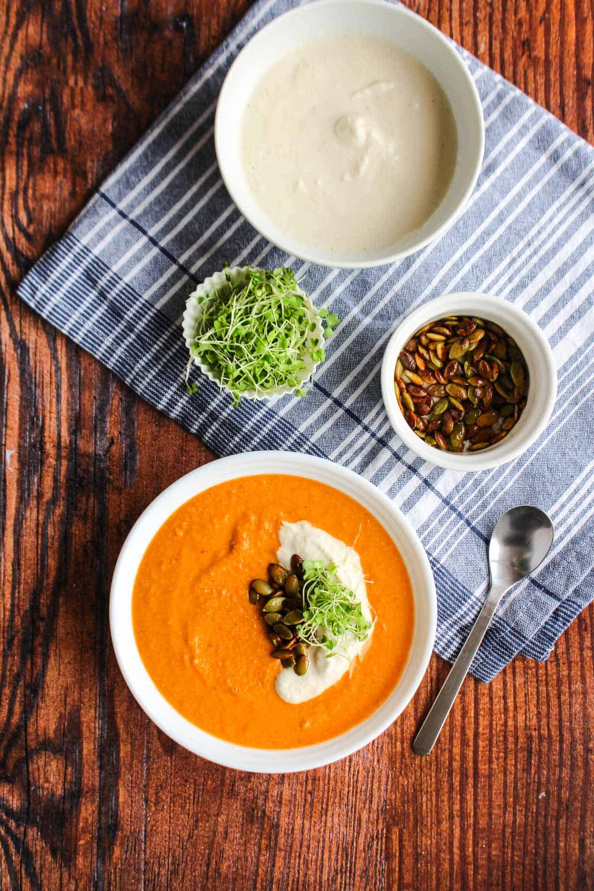 A bowl of tomato chickpea soup on the table topped with cashew cream.
