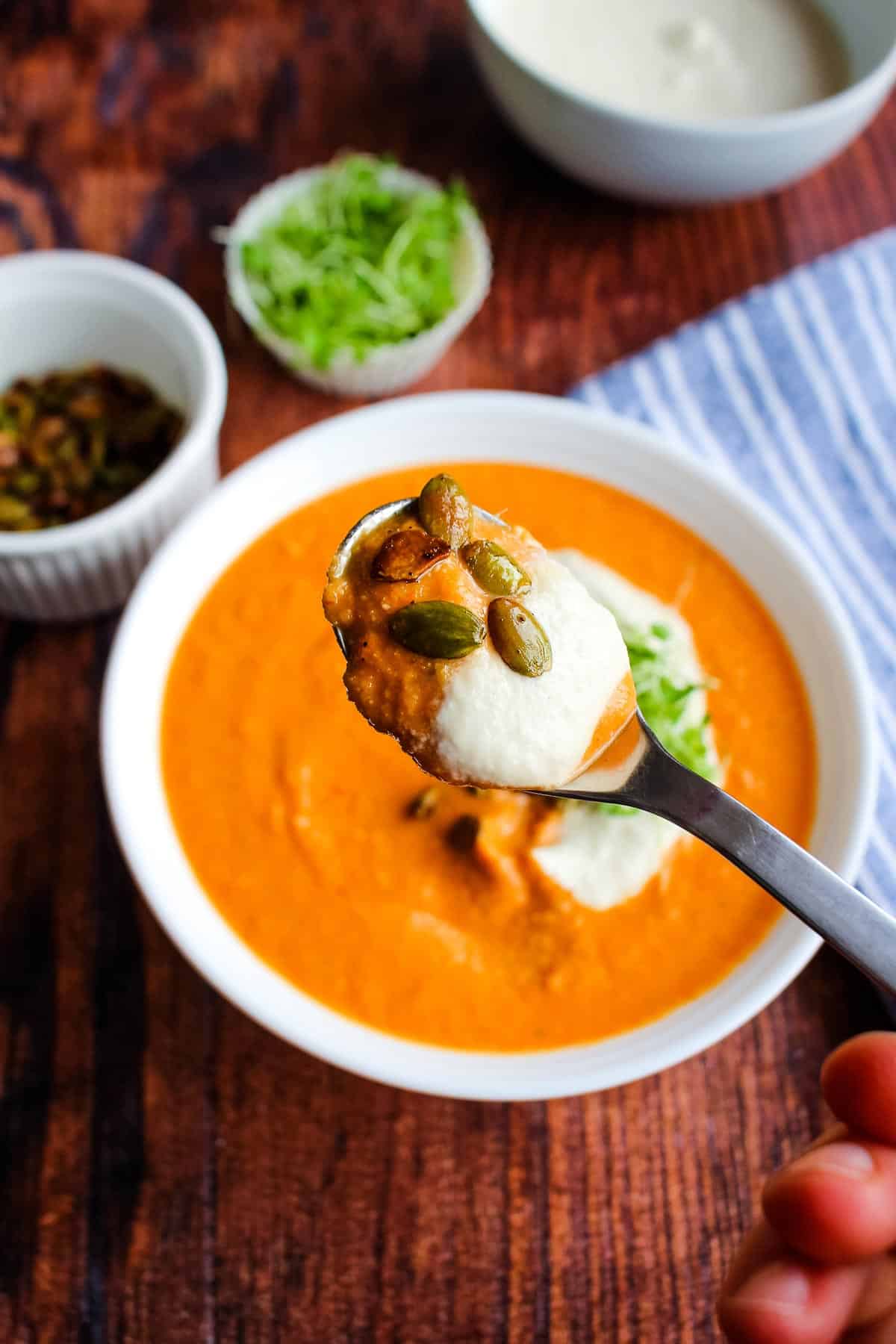 A bowl of chickpea and tomato soup with a spoon lifting a bite out.