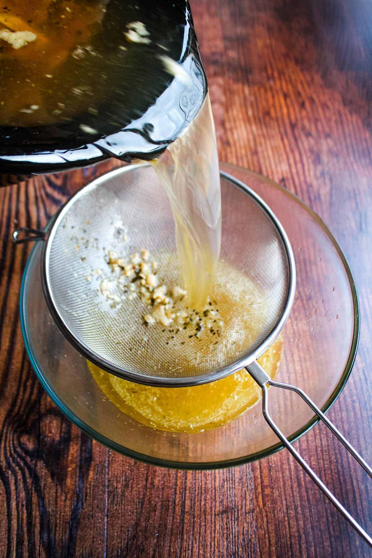 Straining the bone broth to remove bones and solids.