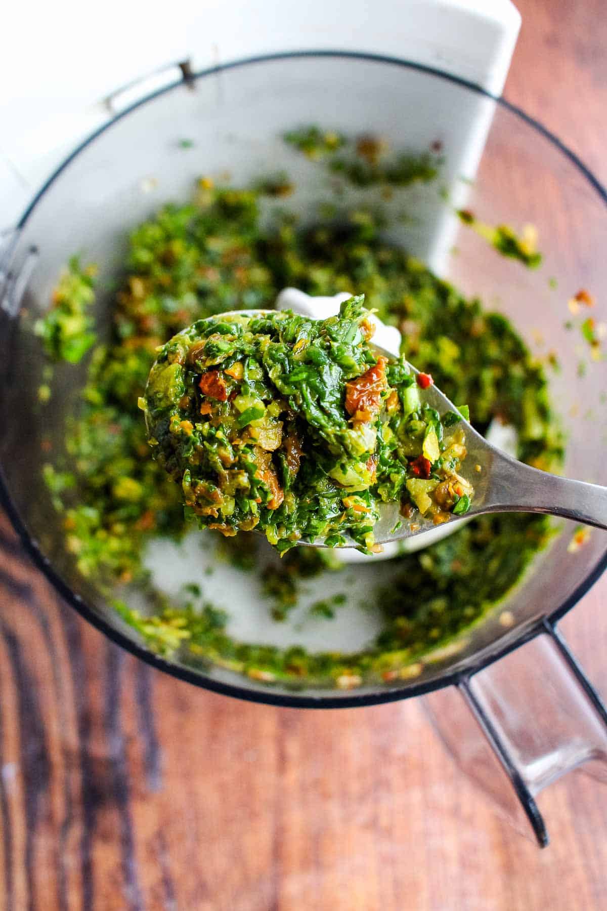 A spoonful of the spinach stuffing on a spoon up over the food processor.