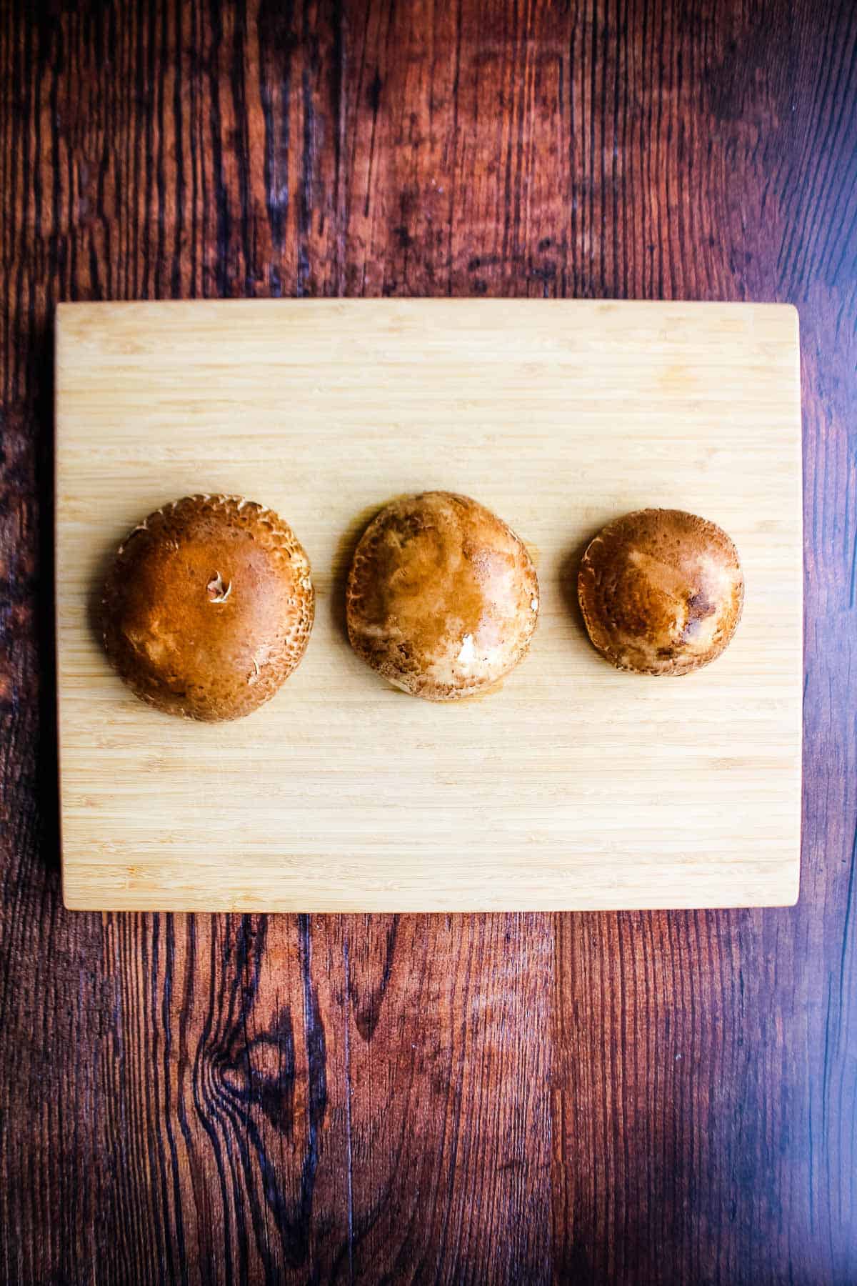 Three portobello mushroom caps on the table ready to prepare.