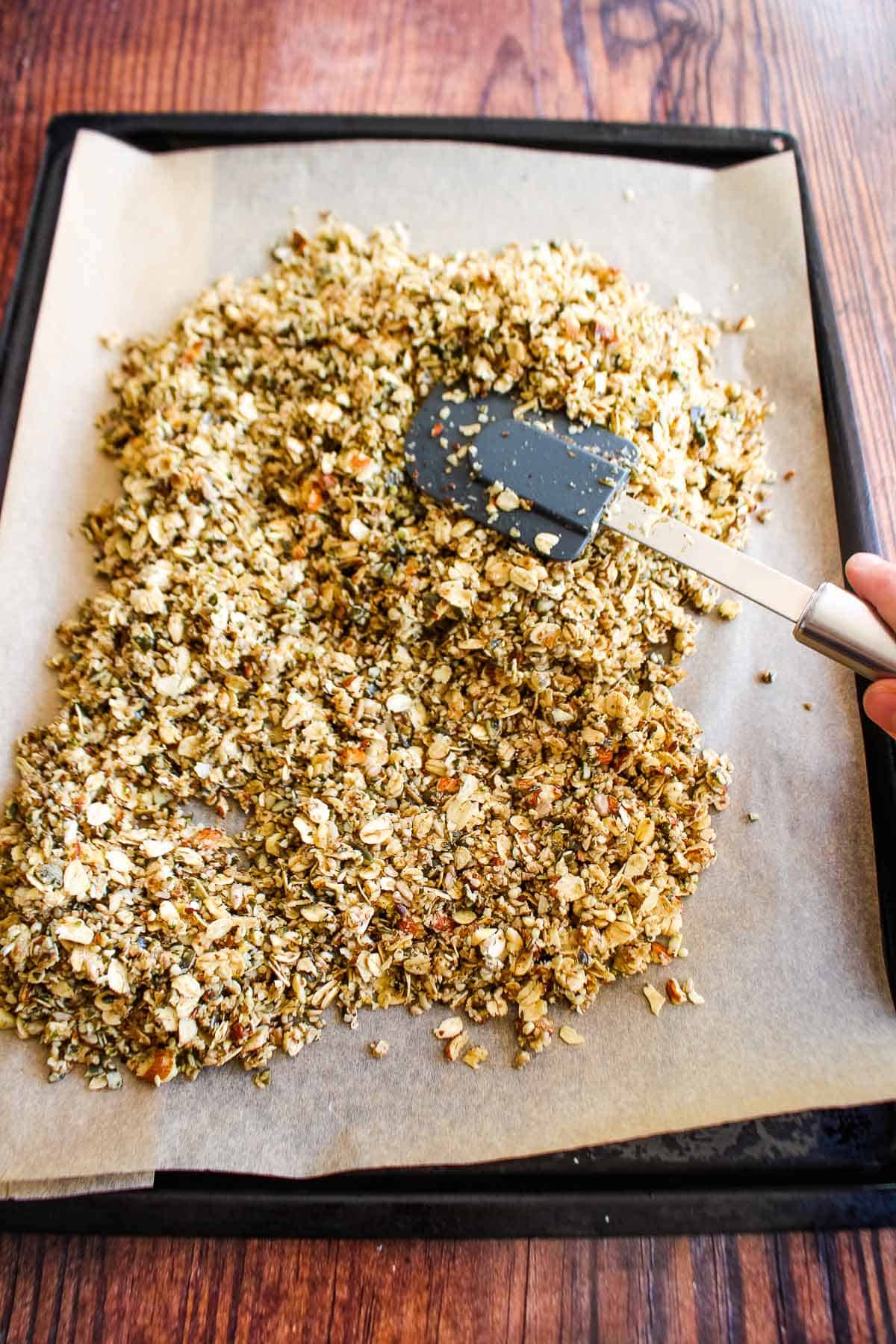 Spreading out vanilla granola on a baking tray.