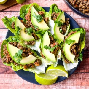 Vegetarian lettuce wraps with lentils on a plate with lime wedges.