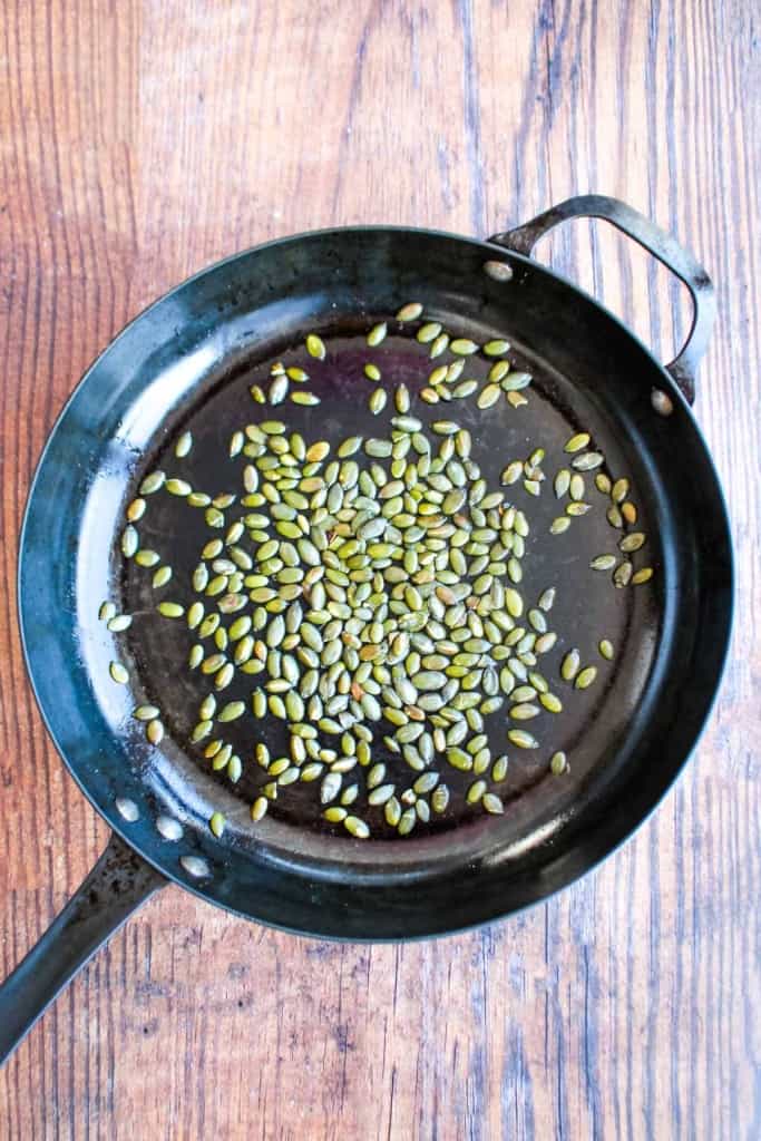 Toasting the pumpkin seeds in a skillet.