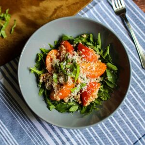 Gluten free salad with grains on the table topped with tomatoes and parmesan cheese.