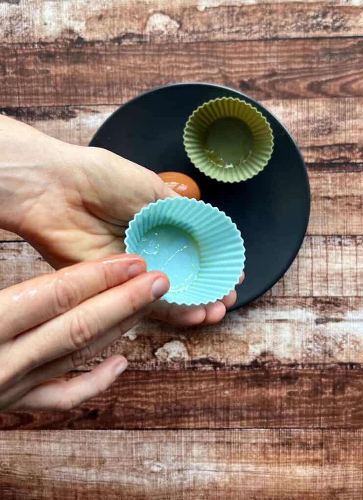 Greasing silicone muffin liners by hand before cracking eggs in them