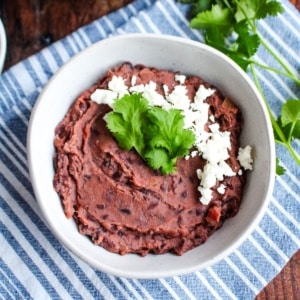 A bowl of black bean dip garnished with cheese crumbles and cilantro.