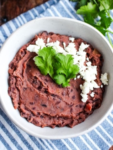 A bowl of black bean dip garnished with cheese crumbles and cilantro.