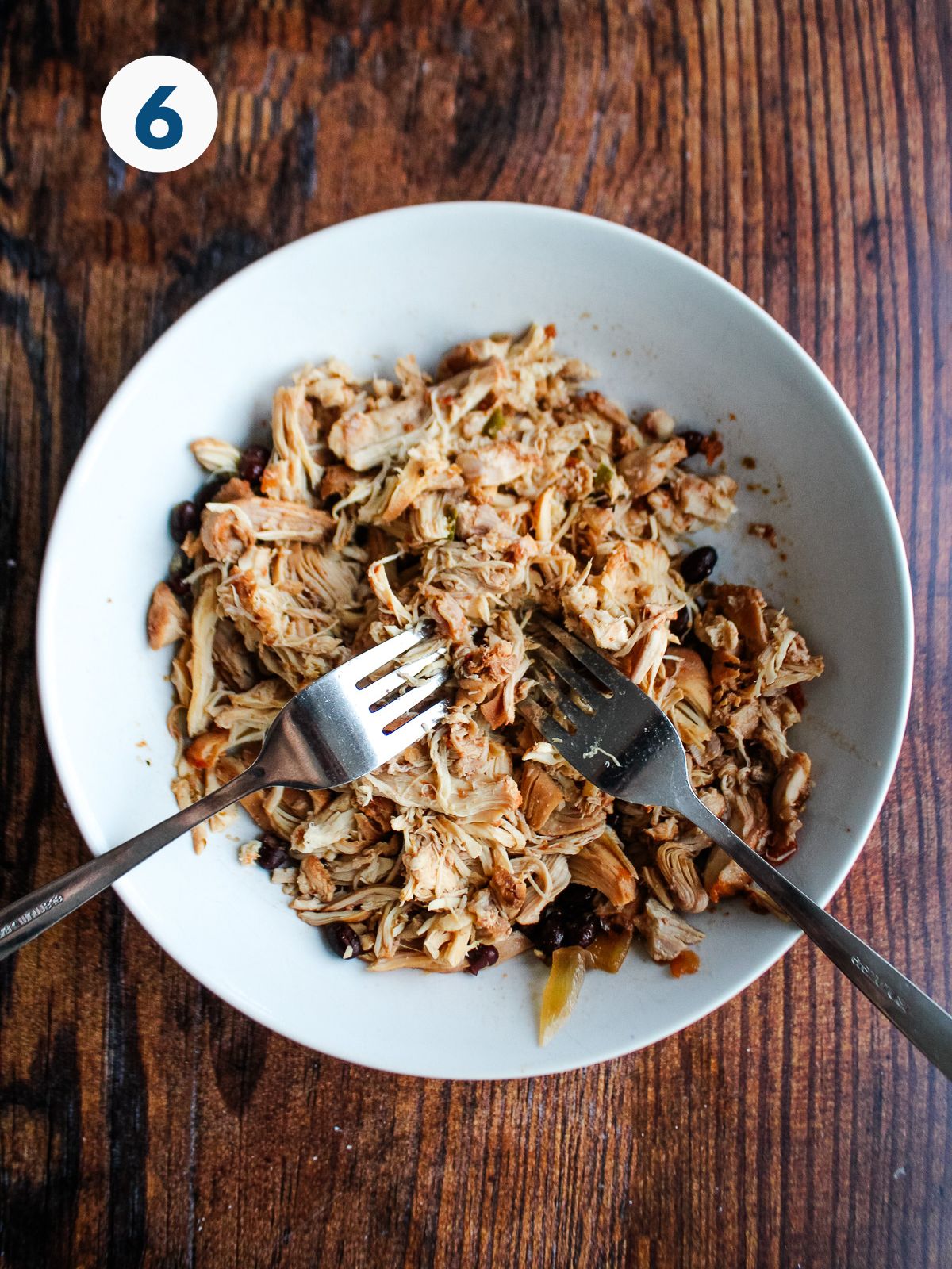 Chicken shredded in a bowl with two forks.