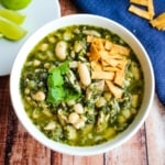 A bowl of Mexican spicy chicken soup on the table topped with crispy tortilla strips.