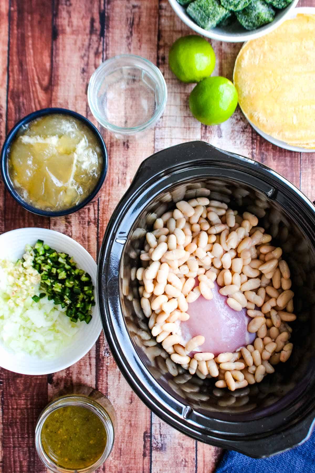 The chicken and beans placed in the bottom of a slow cooker.