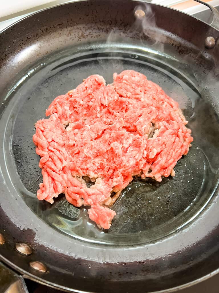 Ground pork browning in a pan
