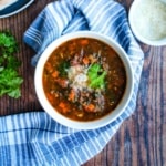 A bowl of Italian sausage spinach soup on the table with a napkin.