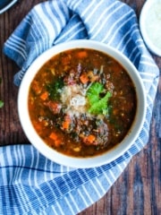 A bowl of Italian sausage spinach soup on the table with a napkin.