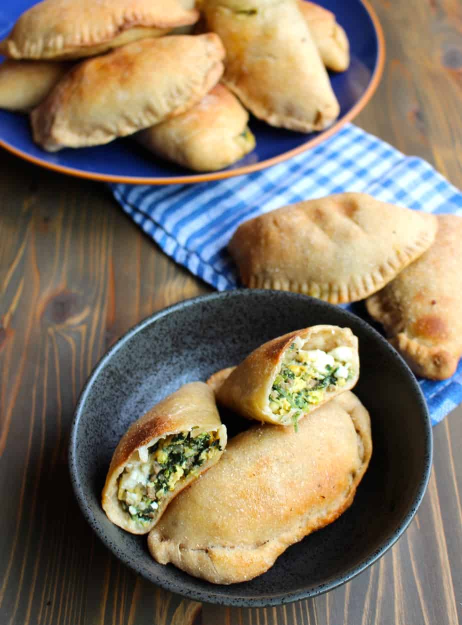 Breakfast Calzones on a plate in the background, on a tea towel in the middle ground, and in a bowl so you can see the filling in the foreground