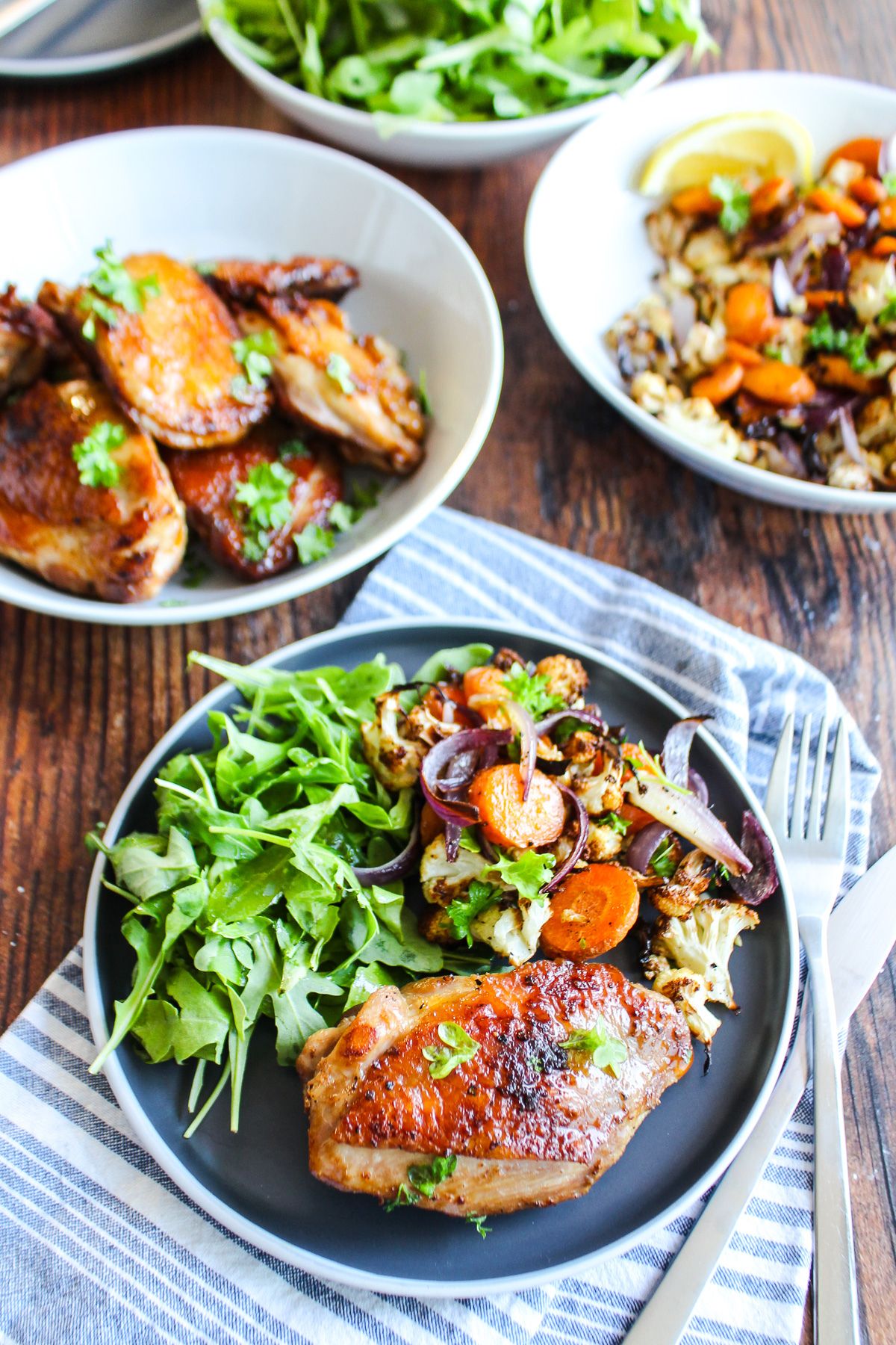 Chicken thighs cast iron skillet on a plate on the table with side dishes in bowls around it.