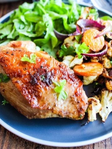 Cast iron chicken thighs served up on a blue plate with sides.