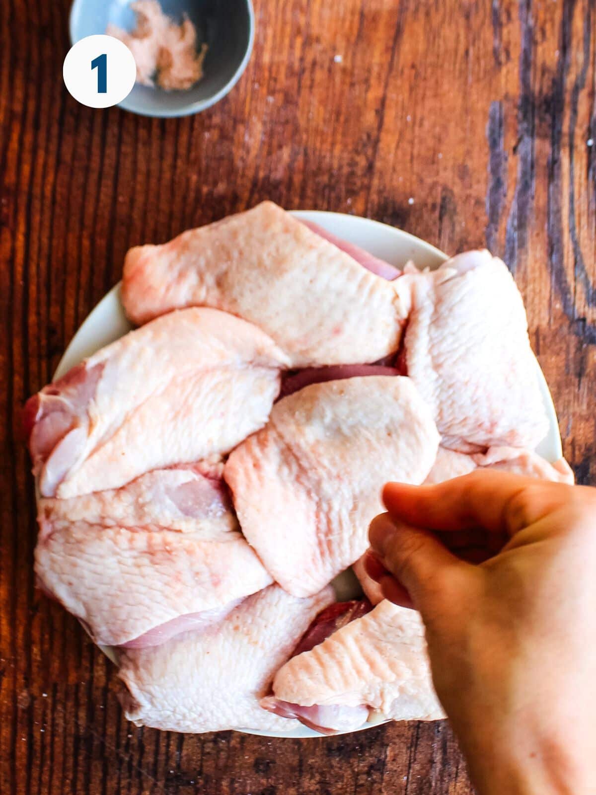 Sprinkling the chicken thighs with seasonings. 