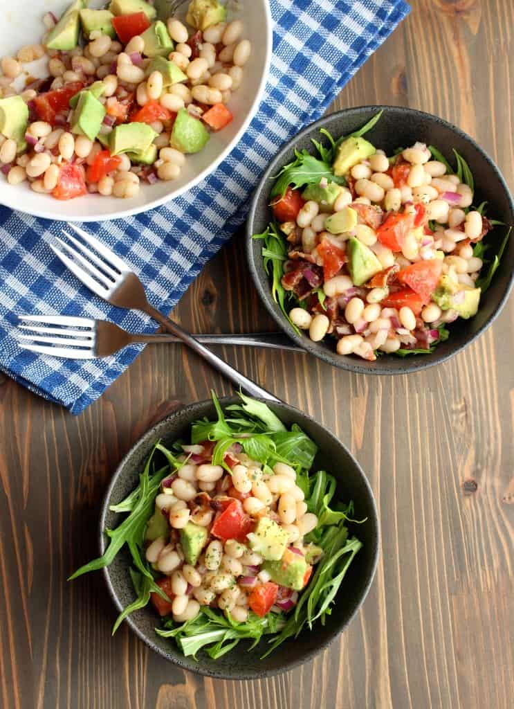 White Bean, avocado, bacon, and tomato in a bowl with leafy greens