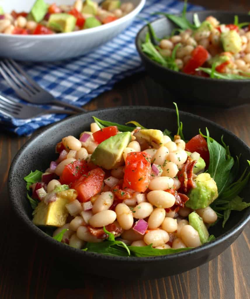 White Bean Avocado Salad with Bacon and Tomatoes by Frugal Nutrition avocado with white beans, bacon, and tomatoes in bowls on a picnic table