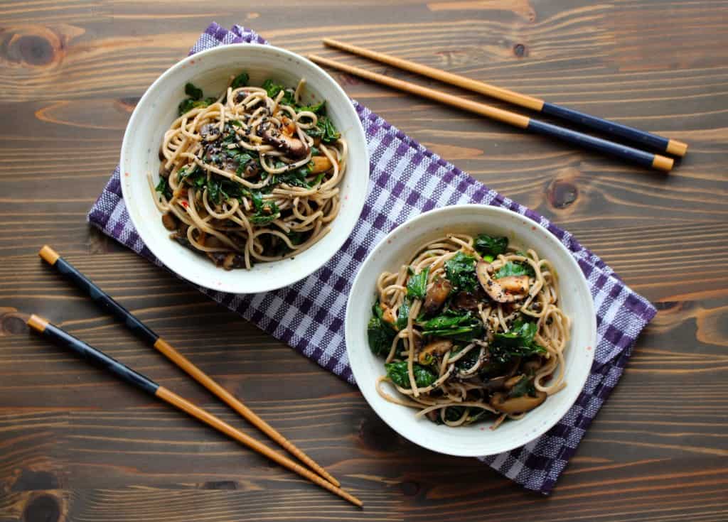 Kale & Soba noodles with garlic butter mushrooms in two bowls and chopsticks beside them