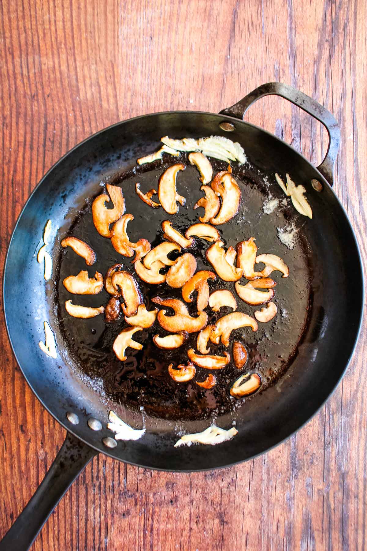 Mushrooms and garlic cooking in a skillet.