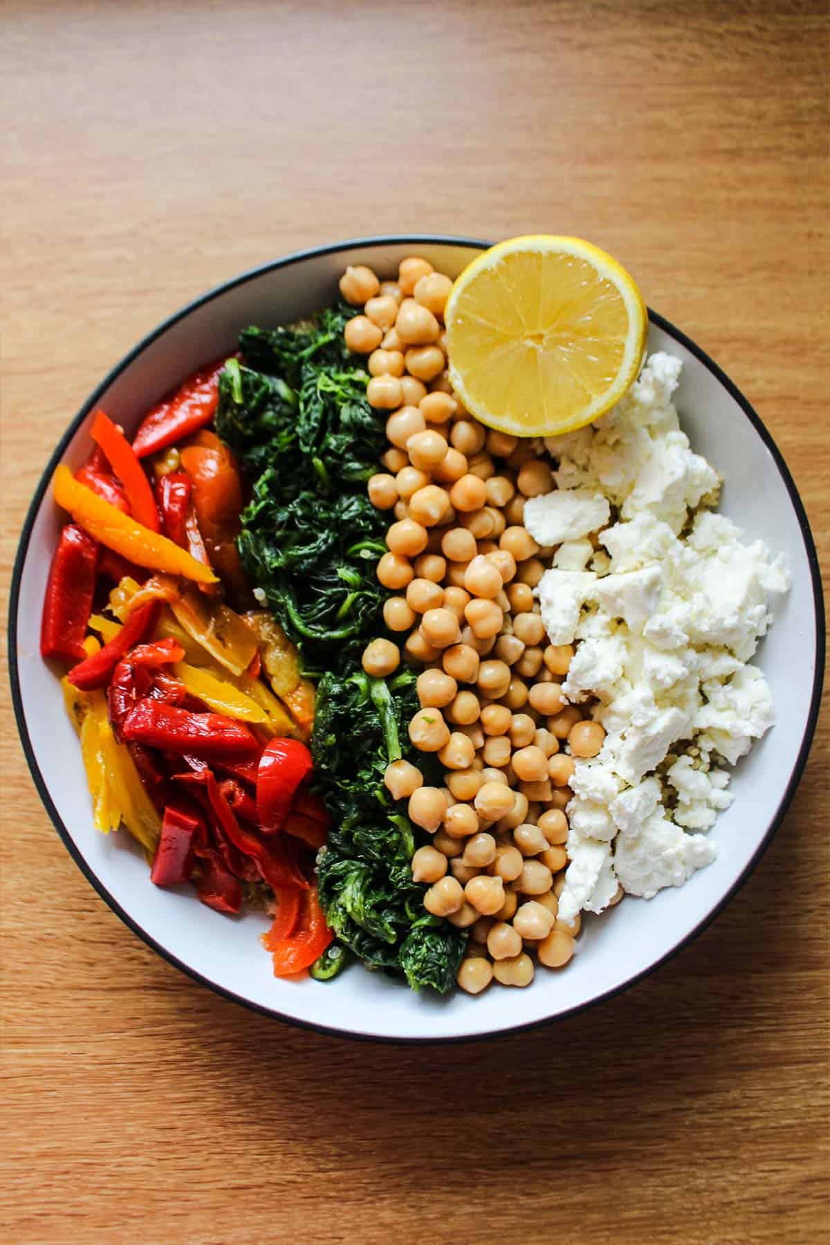 Bowl of spinach couscous with chickpeas, red peppers and feta.