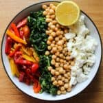 Spinach couscous with lemon and feta served up in a bowl with a lemon for garnish.