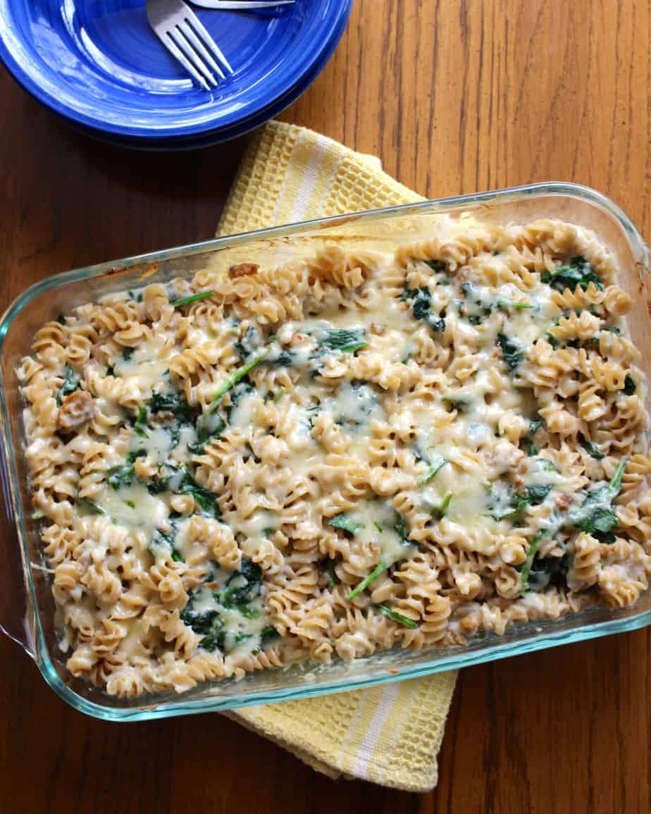 Sausage, spinach, and cheddar mixed with rotini pasta in a casserole dish