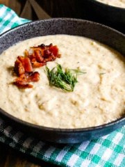 A bowl of cream of celery soup on a checkered napkin on the table.