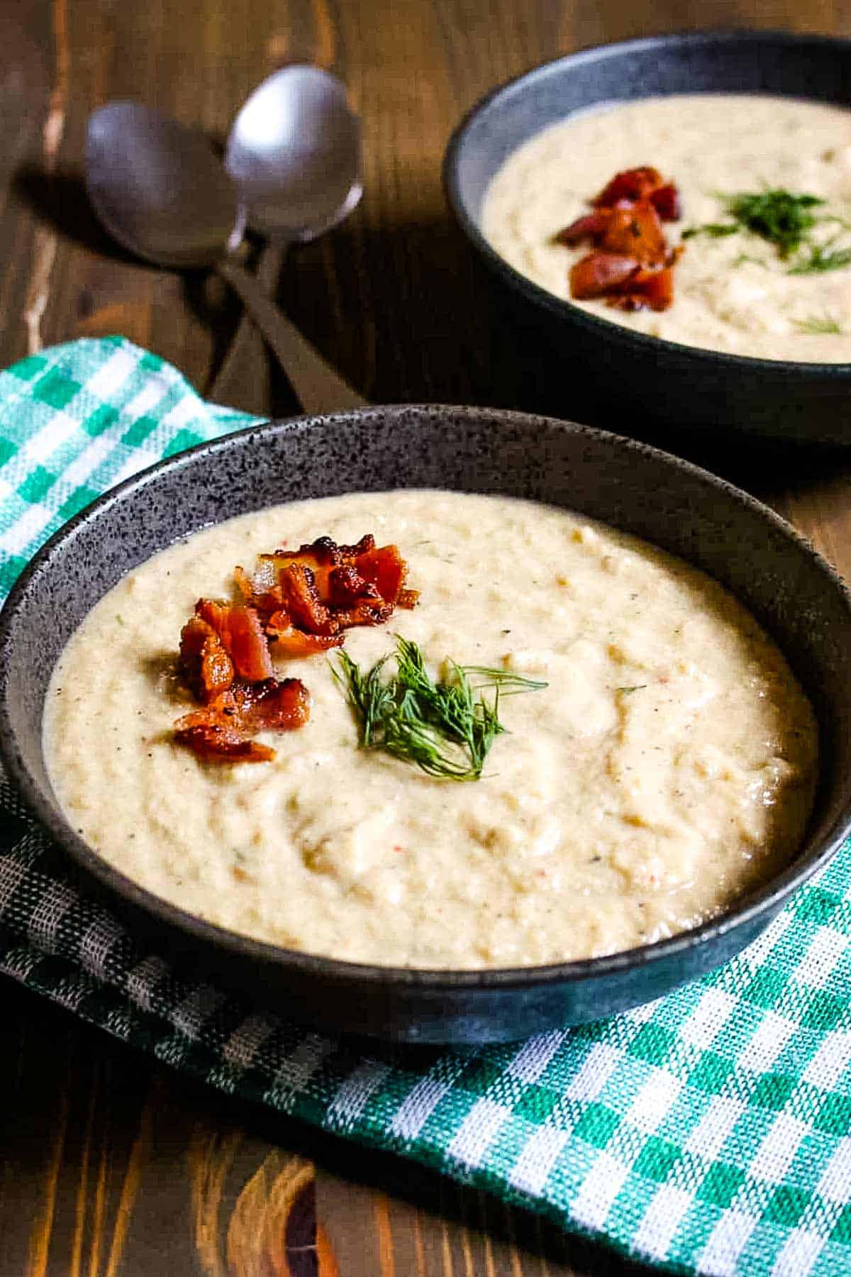 Cream of celery soup in a bowl topped with bacon and fresh dill.