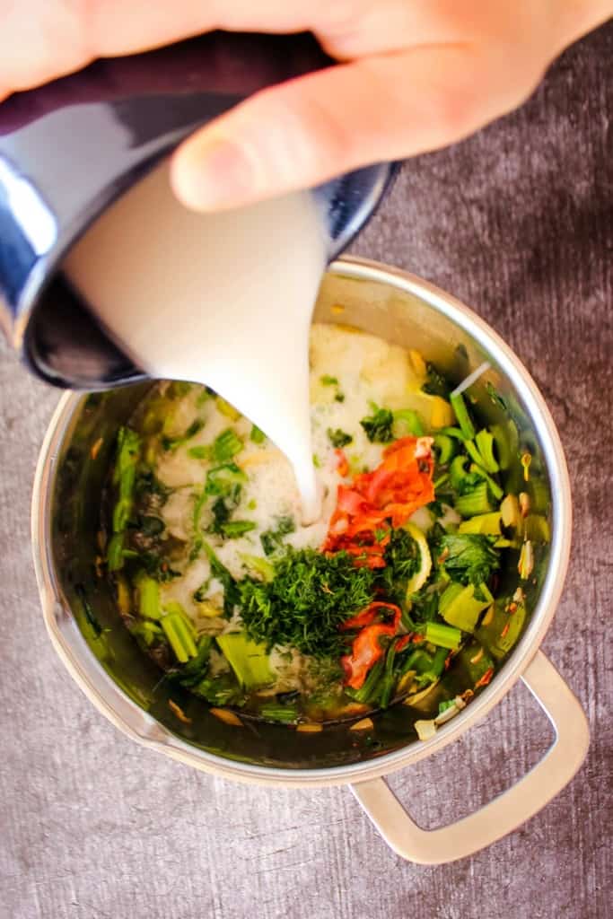 Adding the milk to the pot of veggies.