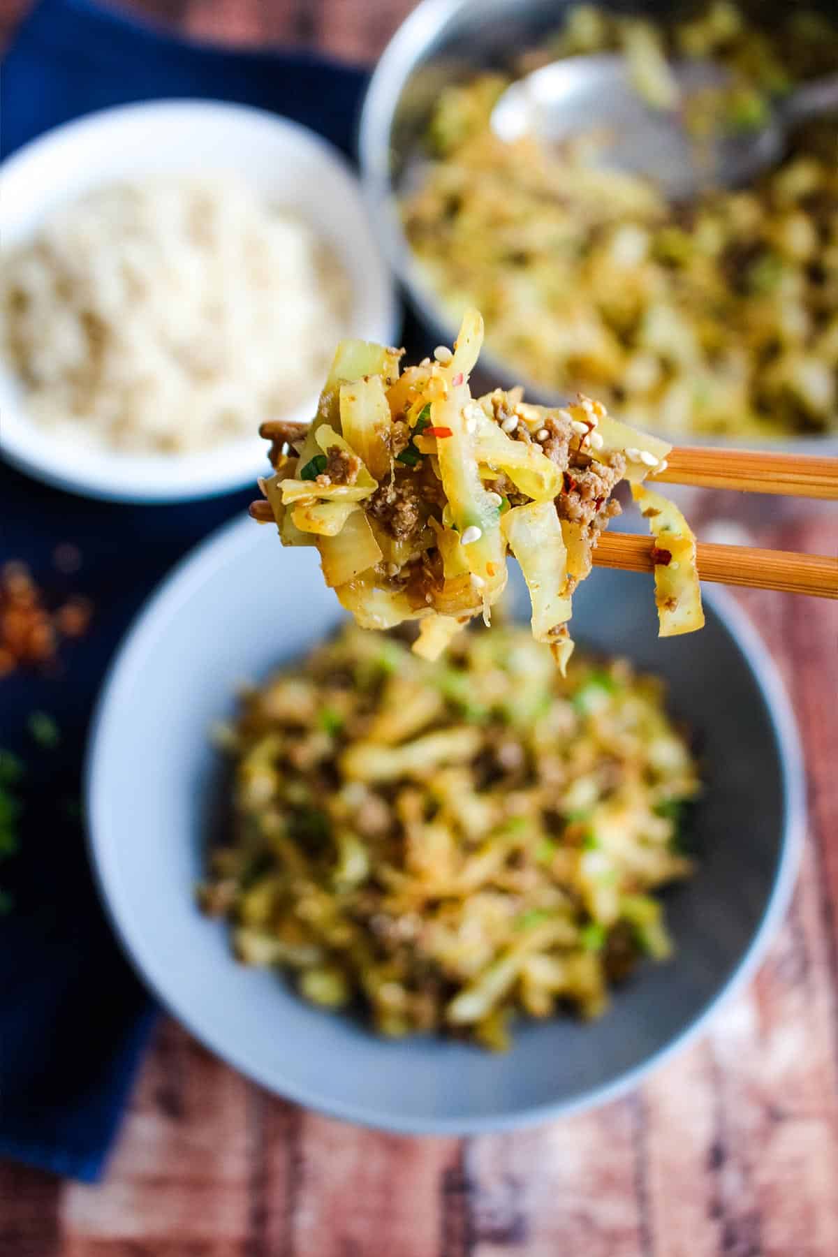 A bite of ground beef and cabbage stir fry on chopsticks.