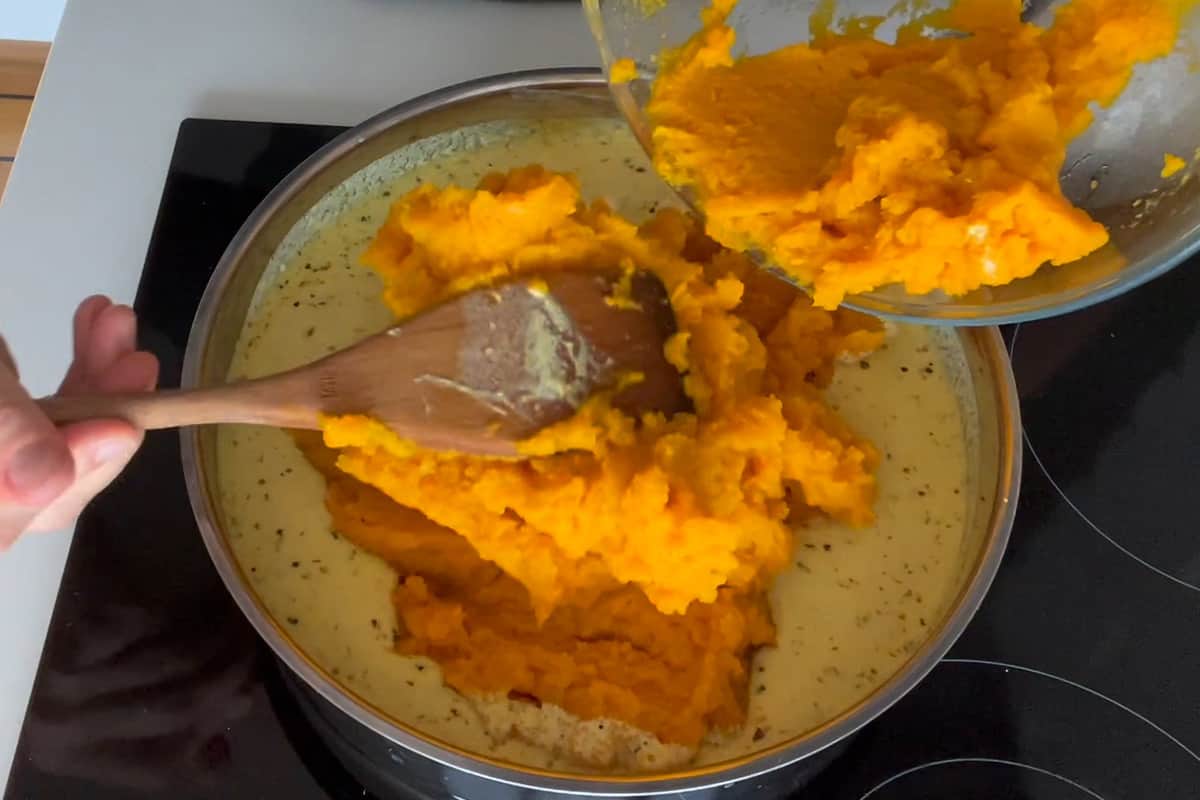 Adding the pumpkin puree to the pan to make the pumpkin sauce for lasagna.