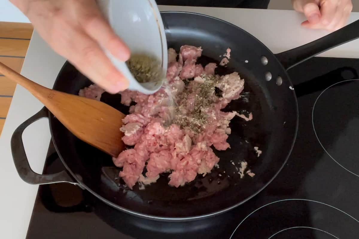 Beef cooking in the pan and adding the spices.