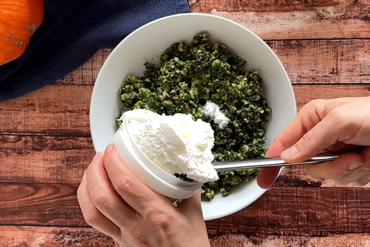 Adding the ricotta cheese to the spinach and beef mixture.