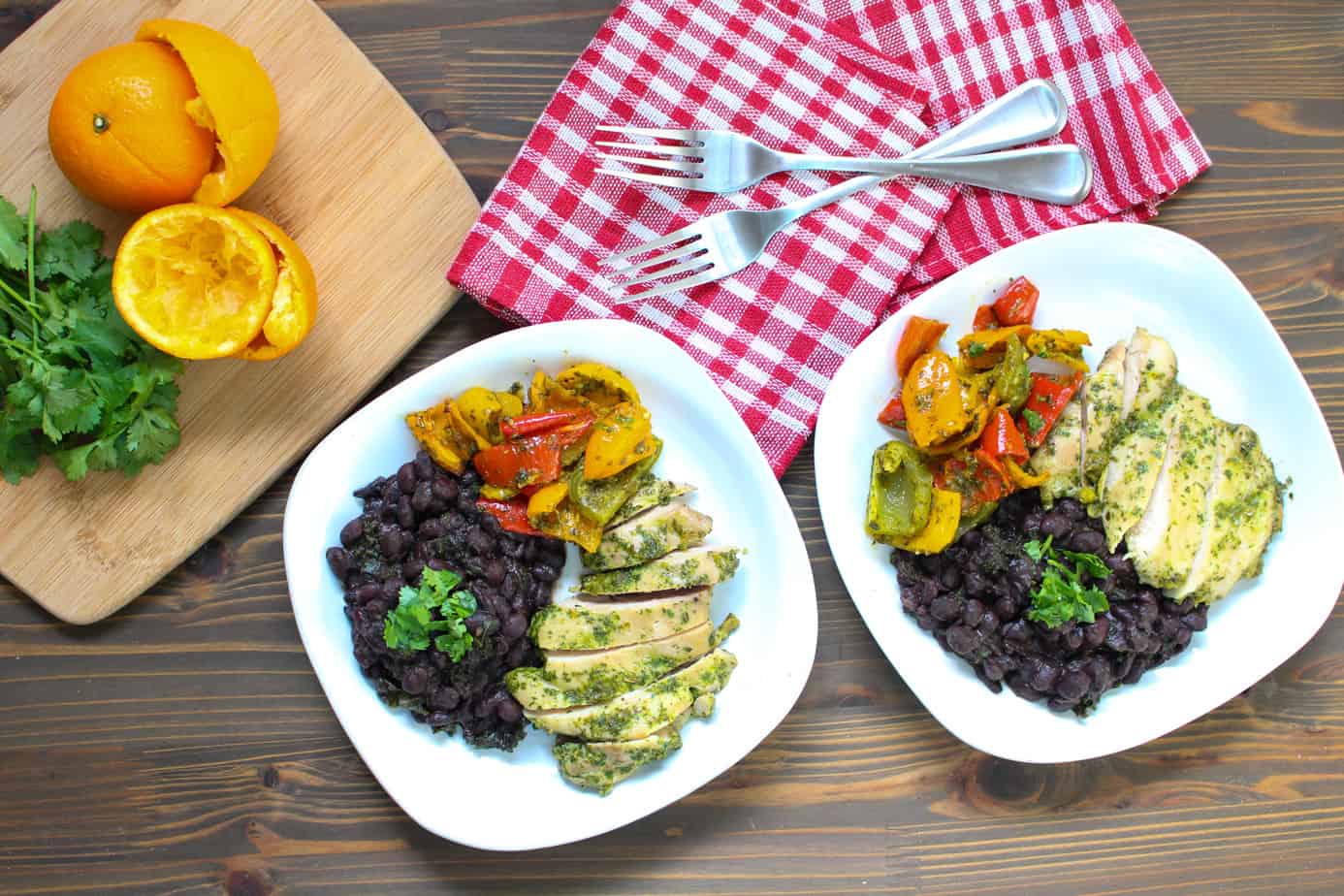 two plates of cilantro orange chicken served with black beans and roasted peppers