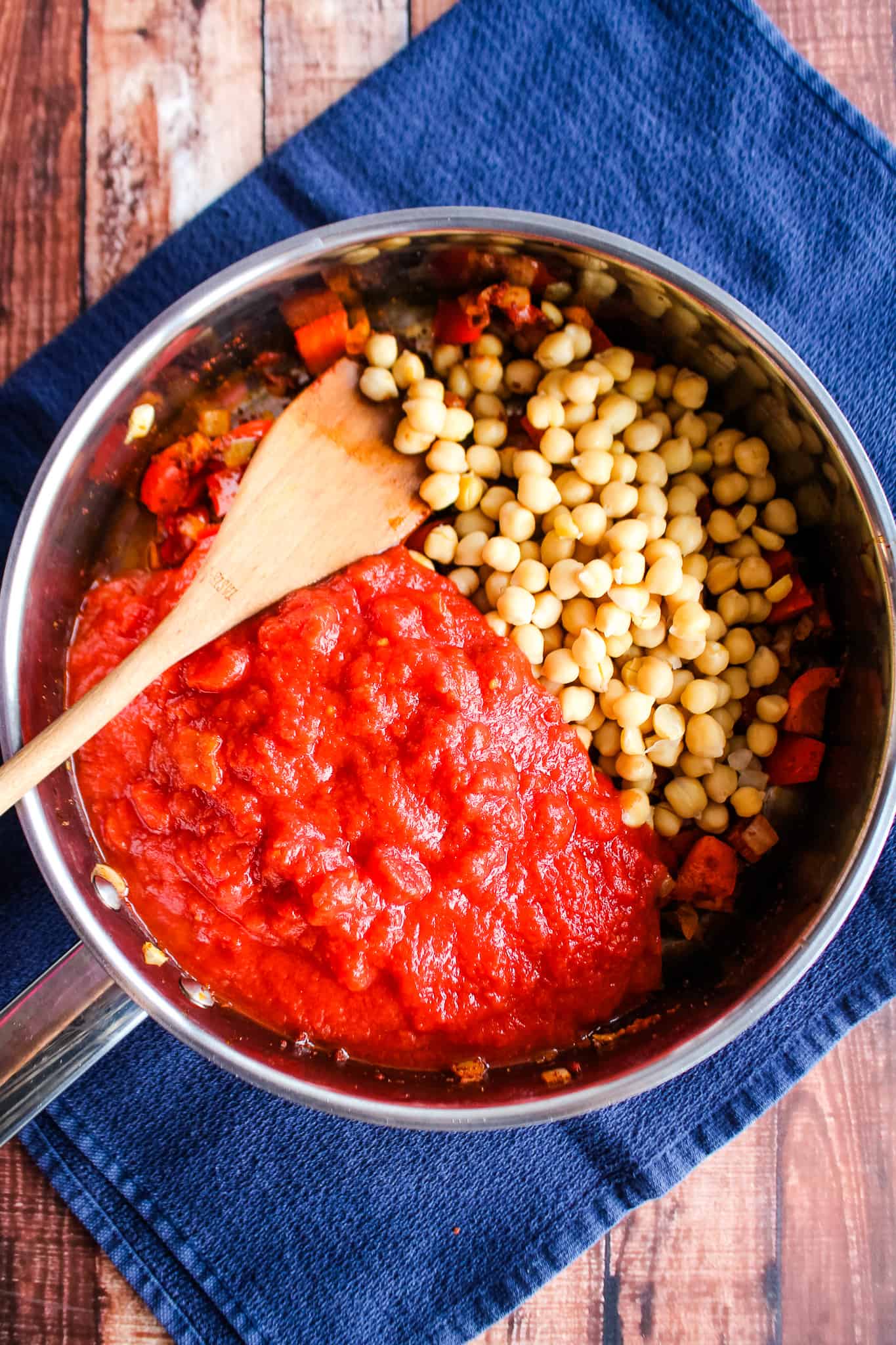 Shakshuka in a skillet with chickpeas and canned tomatoes added on top.