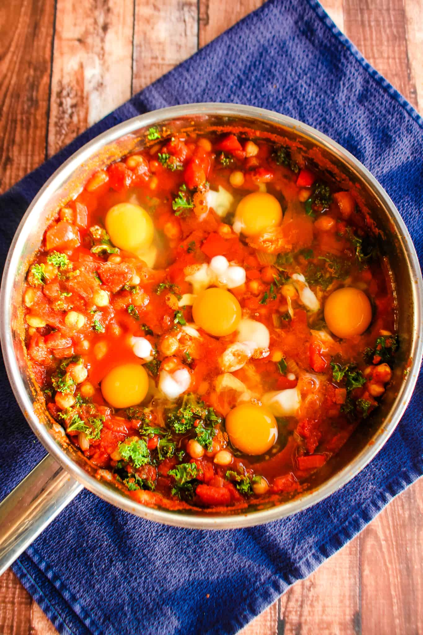 6 raw eggs added to skillet with hot shakshuka sauce.