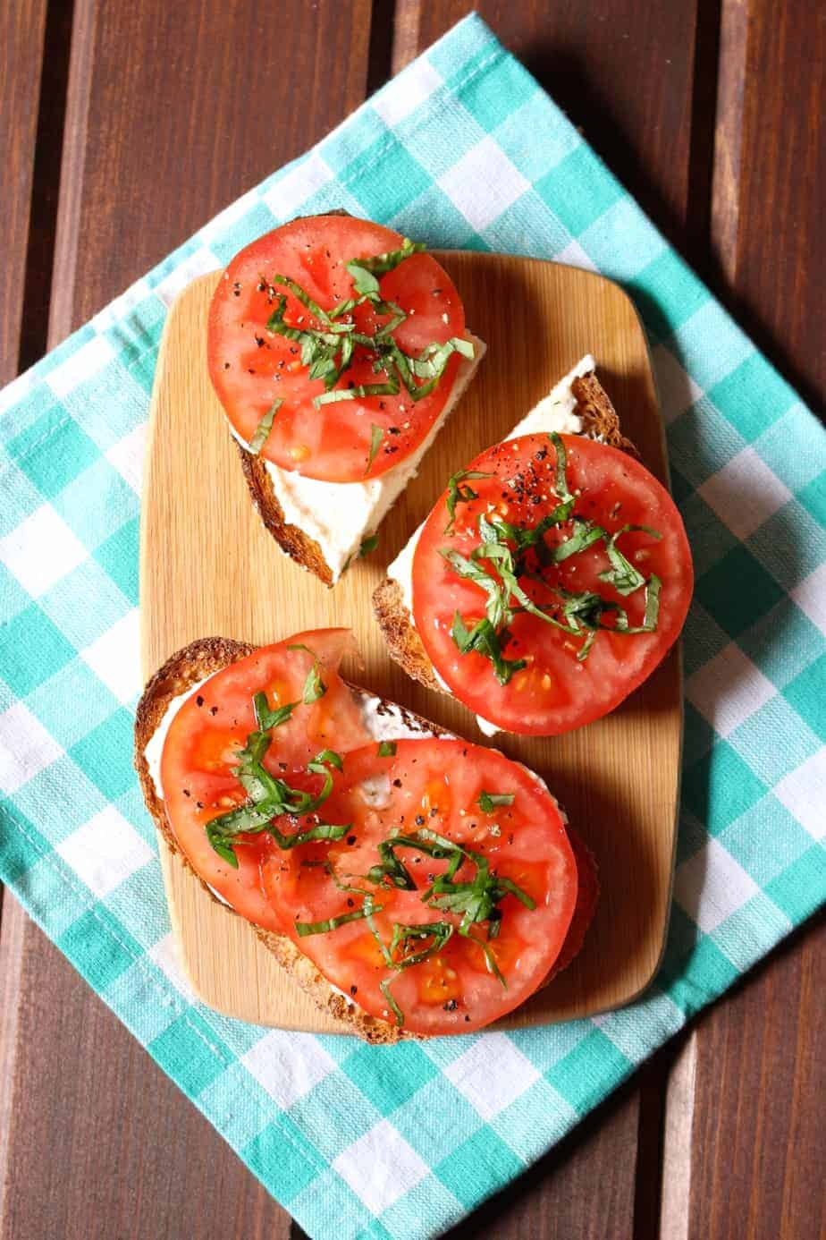 Garlic Ricotta, Tomatoes, Basil on Toast and displayed on a wood serving board