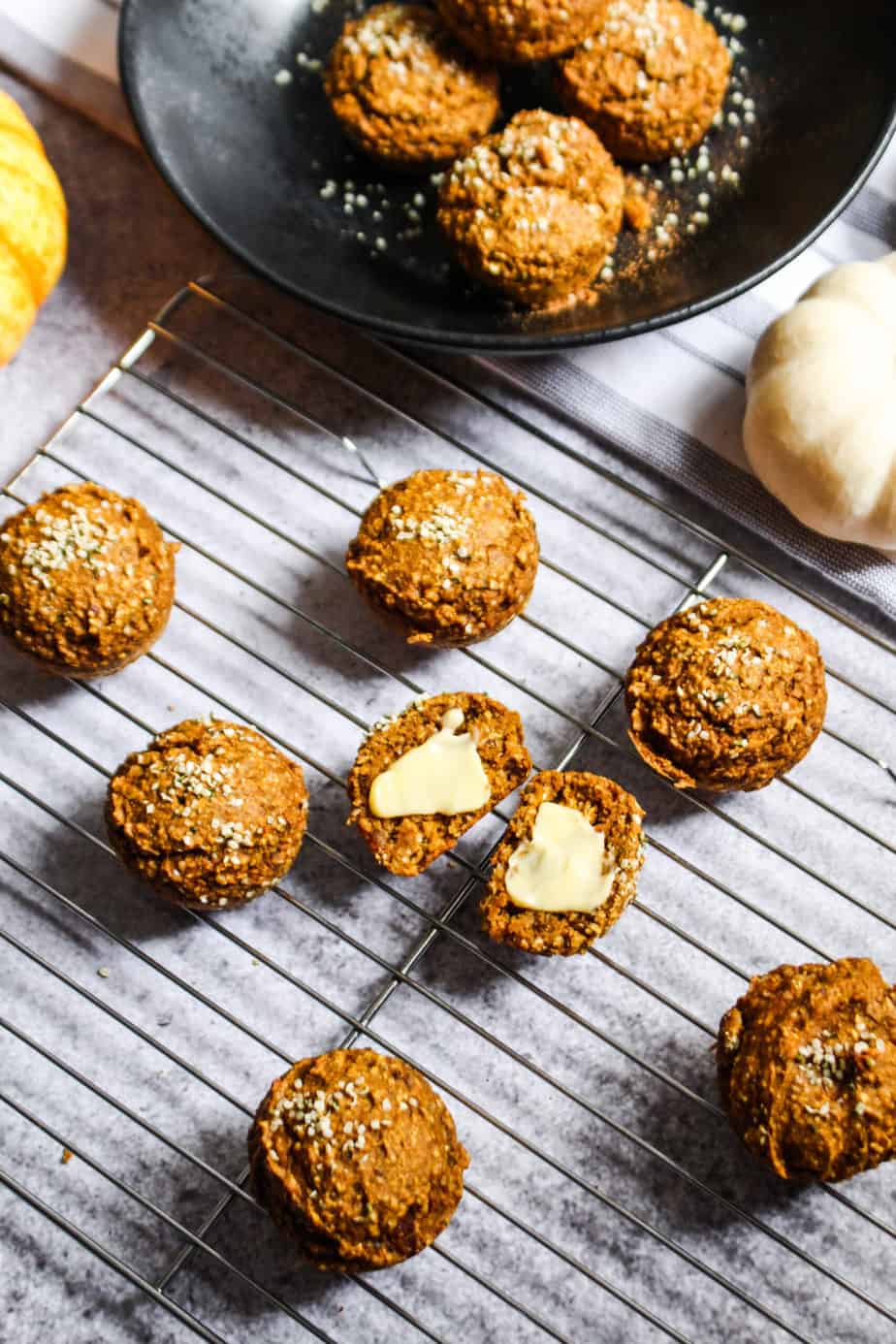 wire rack of pumpkin spice blender muffins centered on one with butter