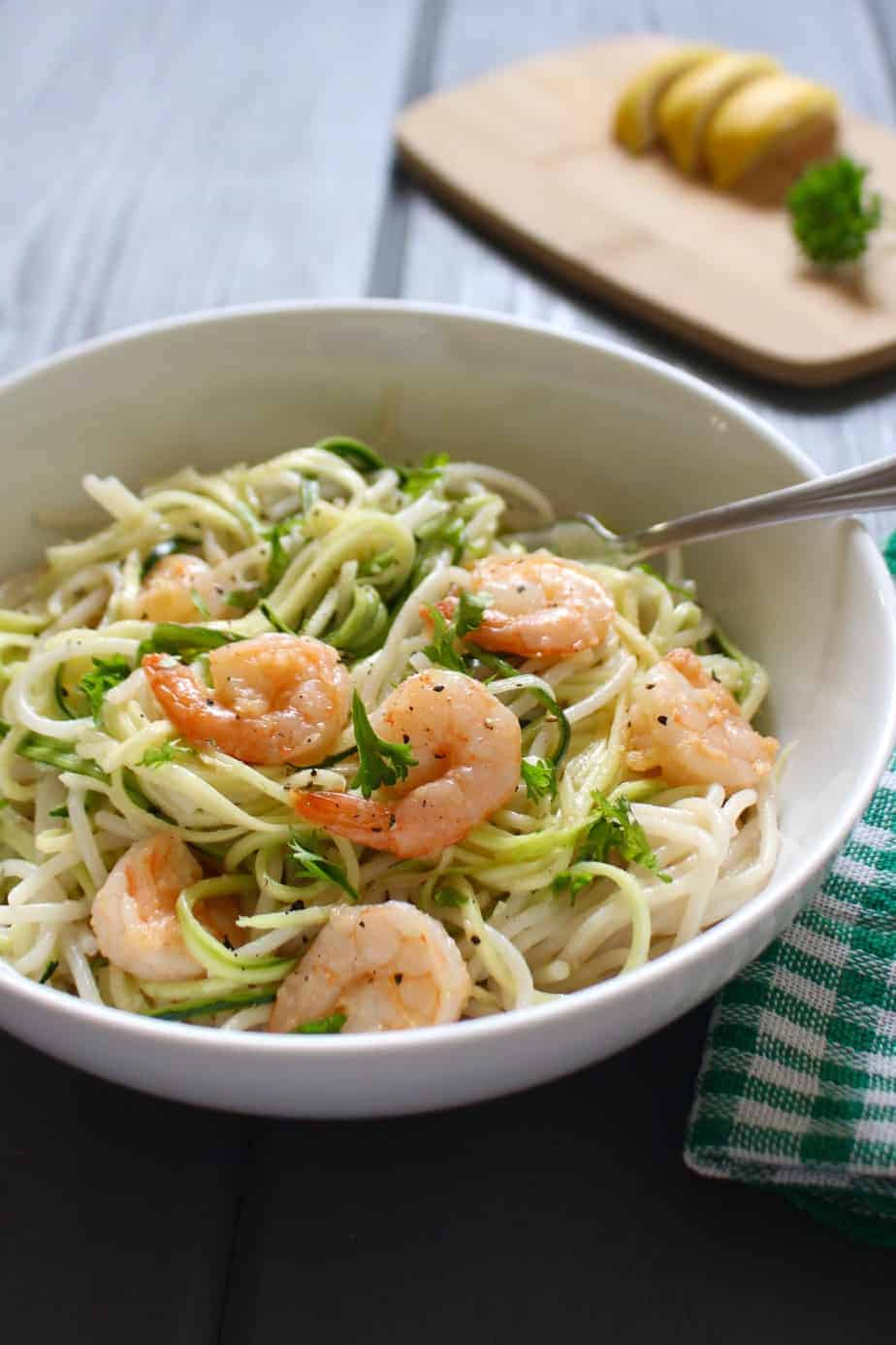 Spicy shrimp with coconut milk, zoodles, and gluten-free pasta in a white bowl