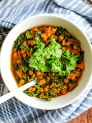 A bowl of lentil kale soup flavored with lemon on the table.