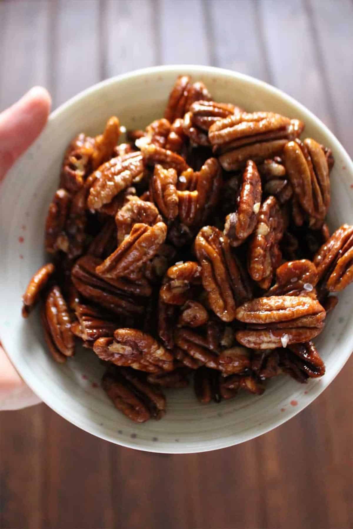 Bowl of spiced pecans held in hands.