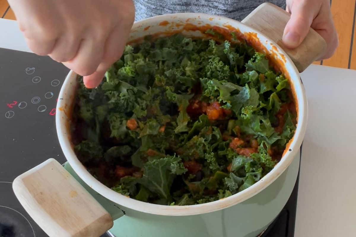 Stirring in the kale to make pumpkin chili.