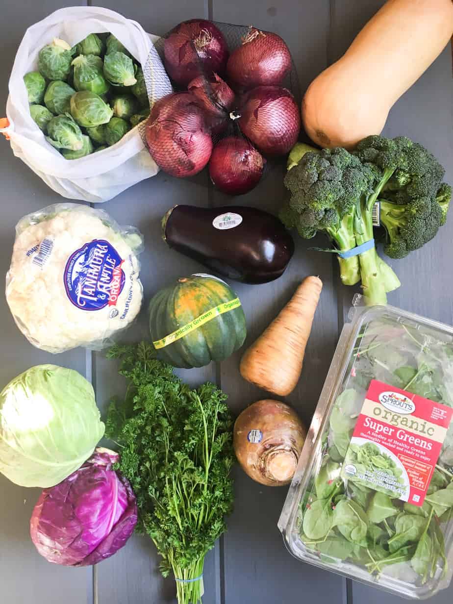 A table covered in various raw vegetables fresh from the grocery store