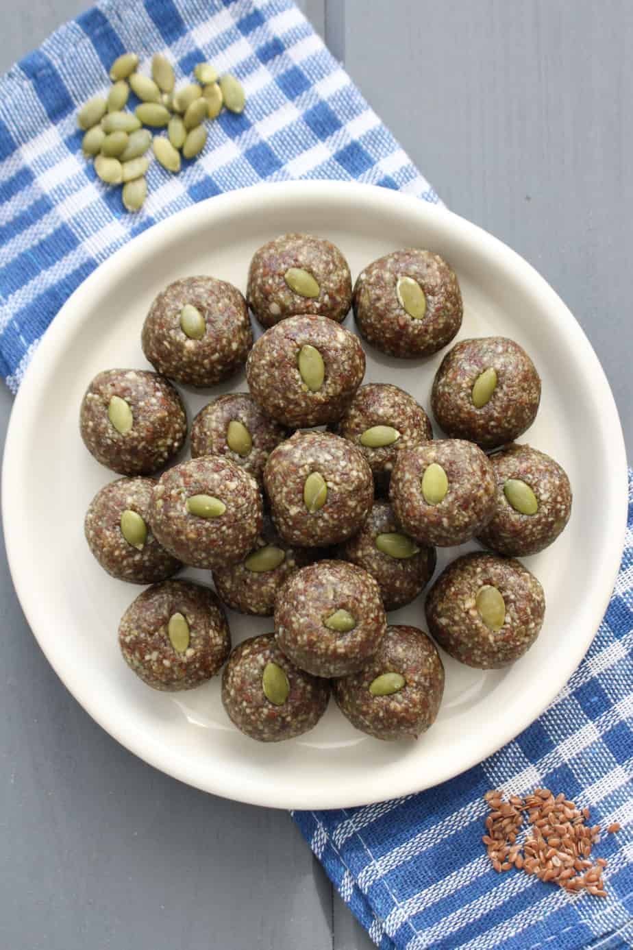 spiced pumpkin bites with pumpkin and flax seeds all rolled into balls with a whole pumpkin seed pressed on top