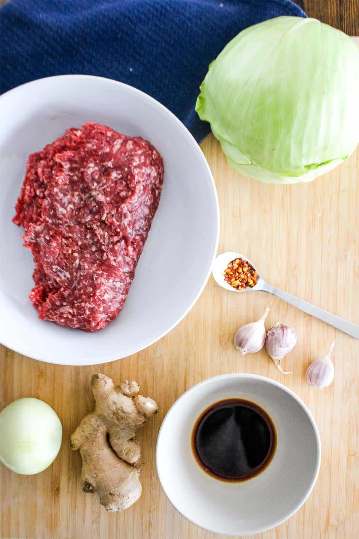 Ingredients to make ground beef and cabbage stir fry on the table.