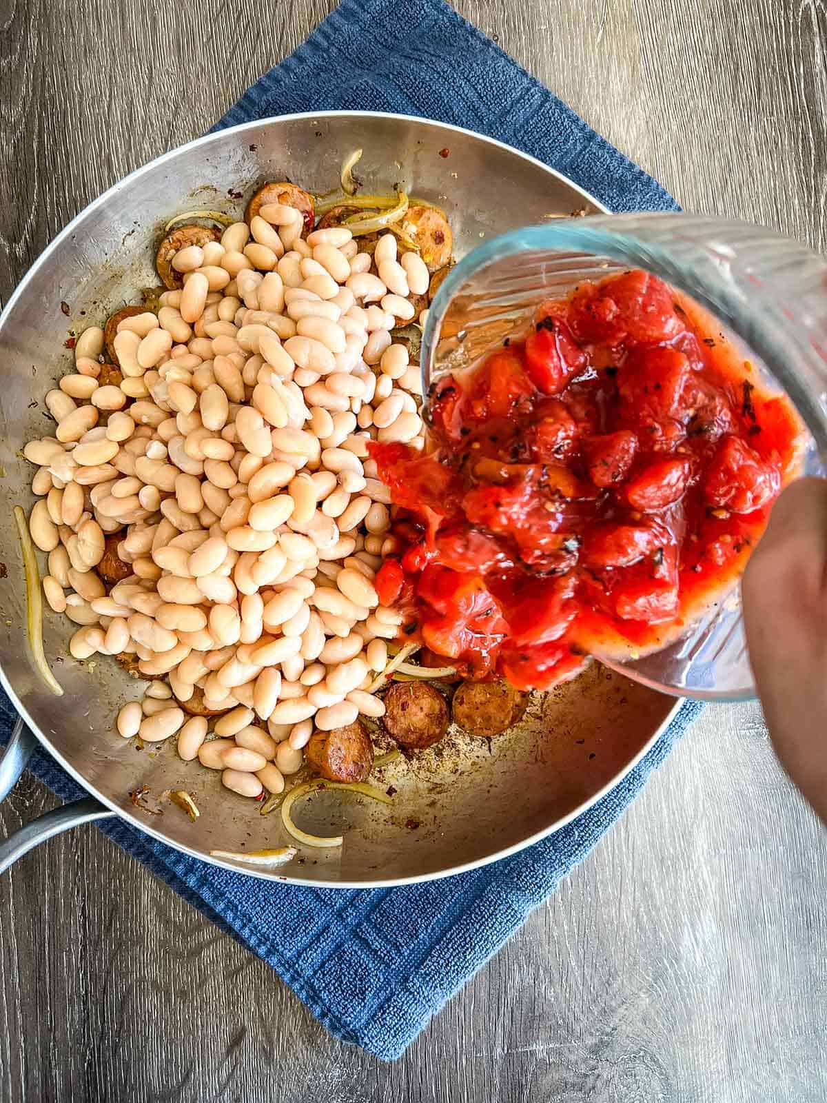 Adding the tomatoes and beans to the skillet.
