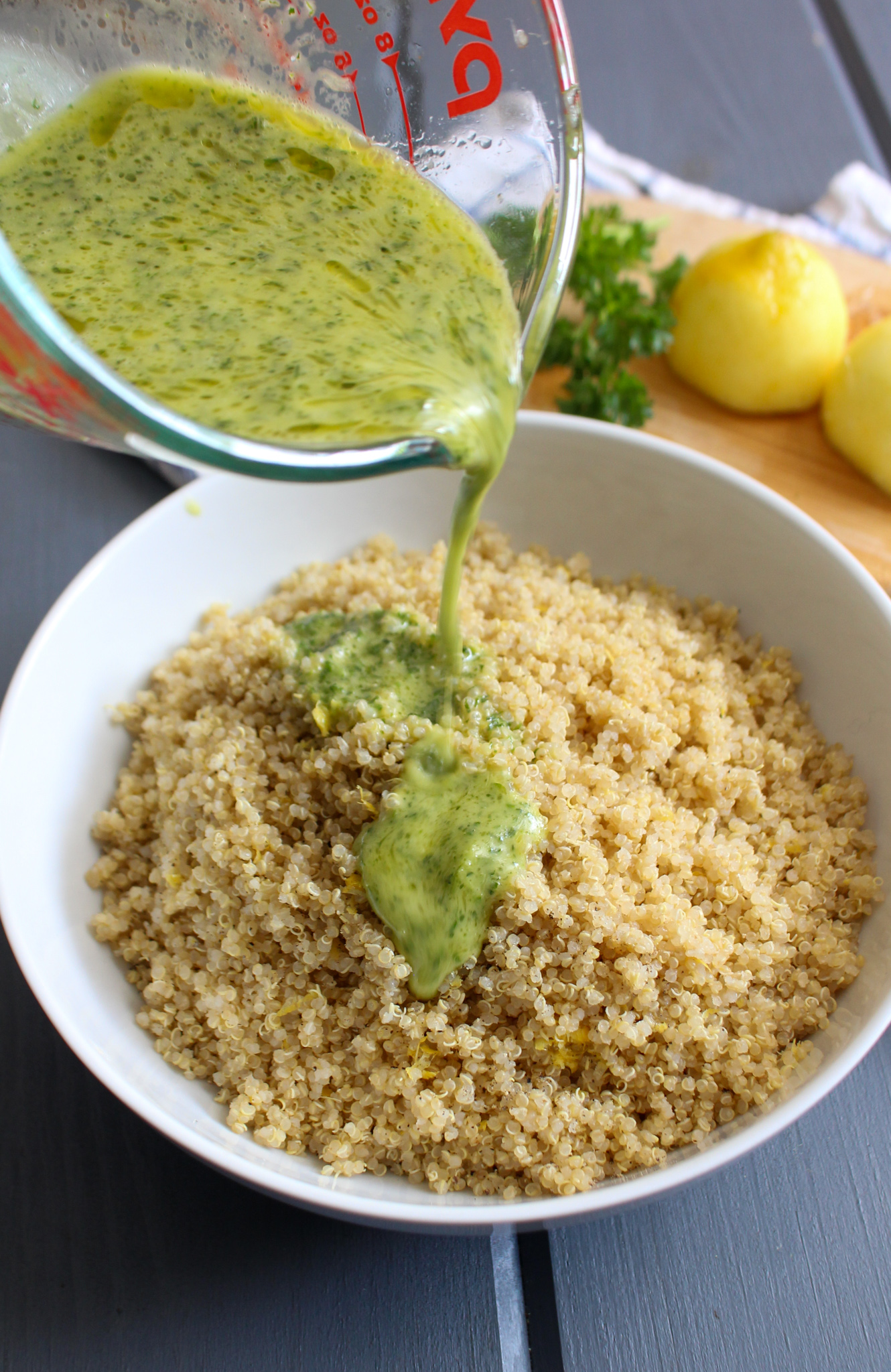 Pouring lemon parsley dressing over lemon quinoa